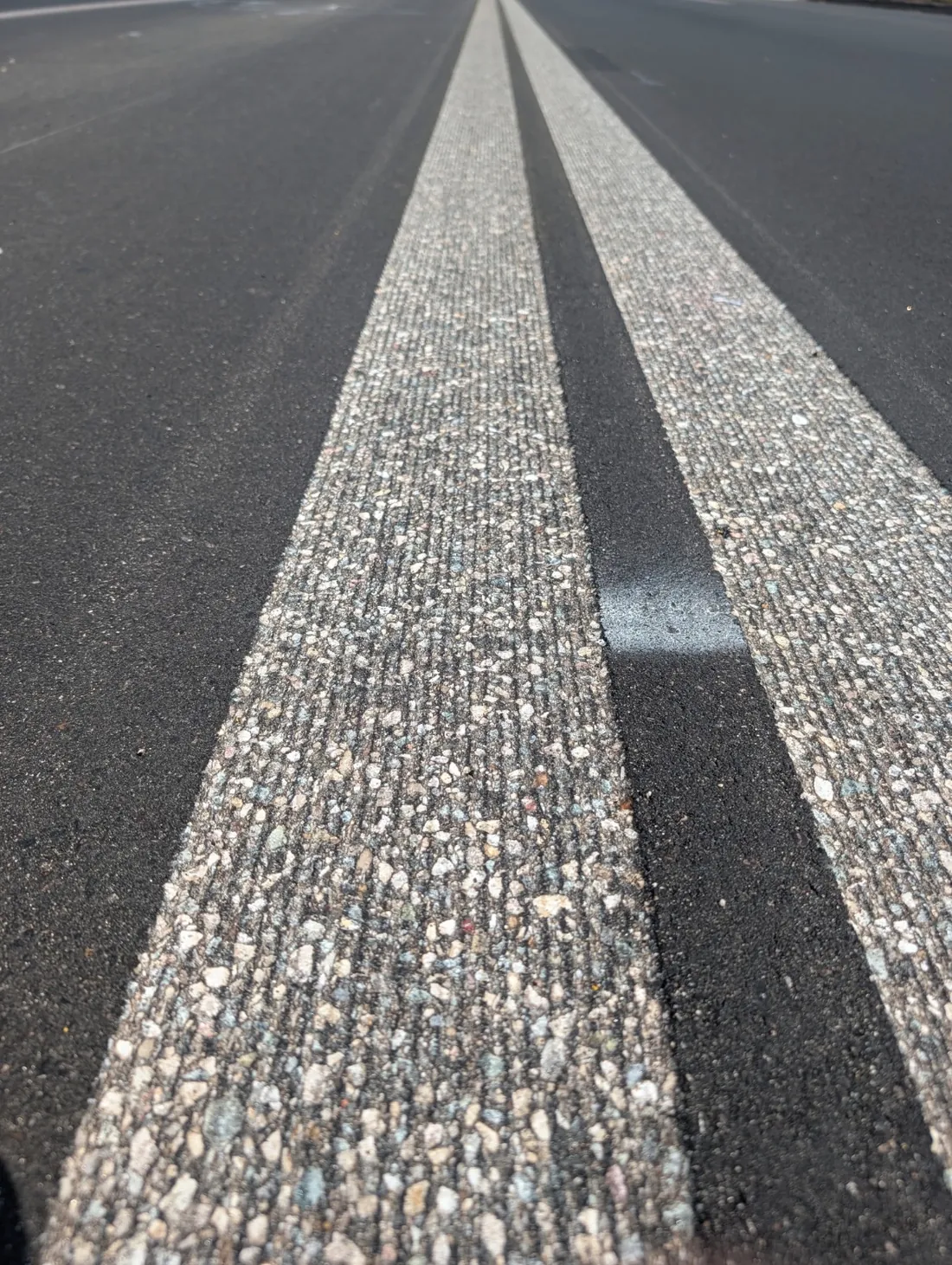 Inset striping grooves ground into asphalt on a live job site
